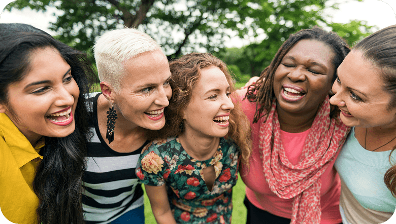 Five women hugging together in a park