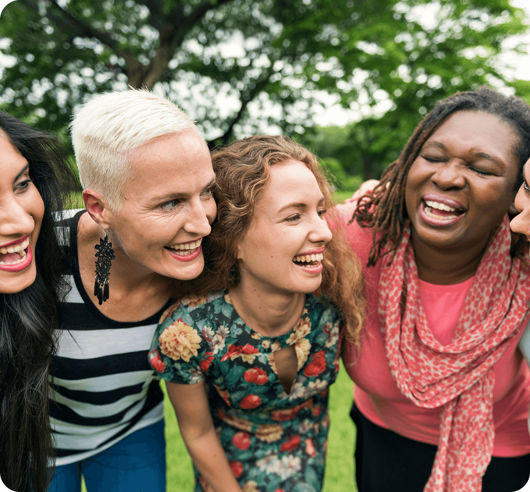 Five women hugging together in a park